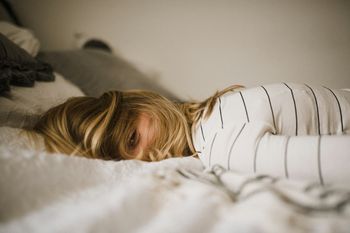 a woman half awake on bed with one eye open